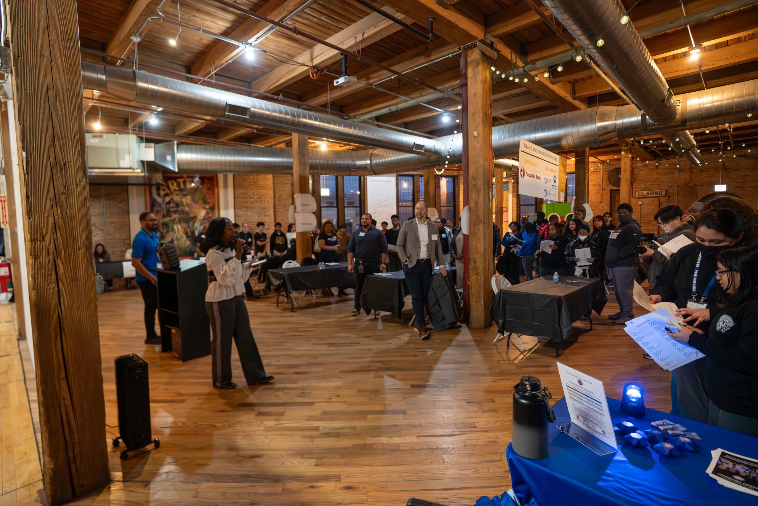 Ama, a black woman, giving a speech to a room of students and mentors